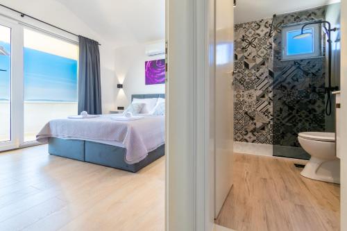 a bedroom with a bed and a bathroom at Penthouse Nensi in Baška Voda