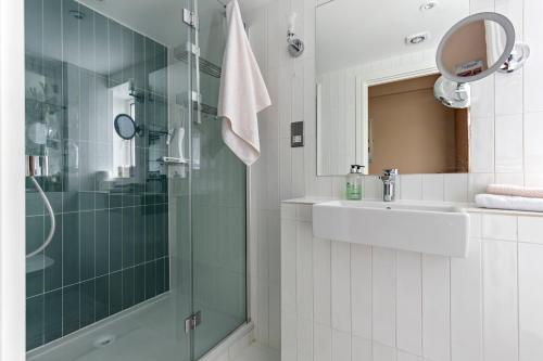 a bathroom with a glass shower and a sink at Westminster Big Ben Apartment in London