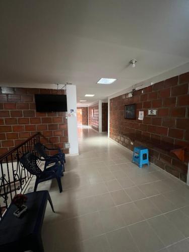 Hostal El Paraiso في Jamundí: غرفة بجدار من الطوب مع تلفزيون وكراسي