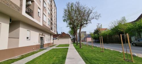 a sidewalk next to a building with a grass yard at Apartman Visnja in Subotica
