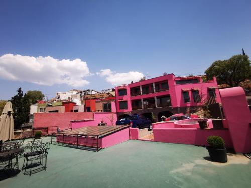 a group of pink buildings with tables and chairs at Hotel Chocolate Suites in Guanajuato