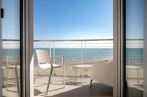a view of the beach from a balcony with a table and chair at Hotel Marco Polo in Caorle