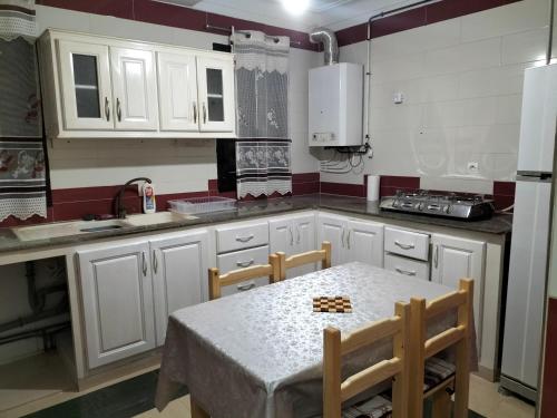 una cocina con armarios blancos y una mesa con sillas. en MAÏS en Argel