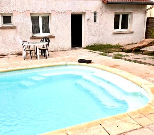 une grande piscine avec deux chaises et une table dans l'établissement L’annexe, à Lunéville