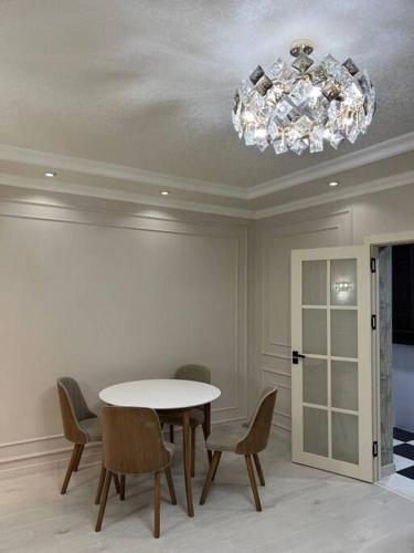 uma sala de jantar com uma mesa e cadeiras e um lustre em Miracle Apartment em Samarkand