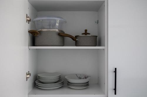 einen Schrank mit Tellern und Geschirr darin in der Unterkunft Pagani Blue - Luxury Studio A2 in Faraí