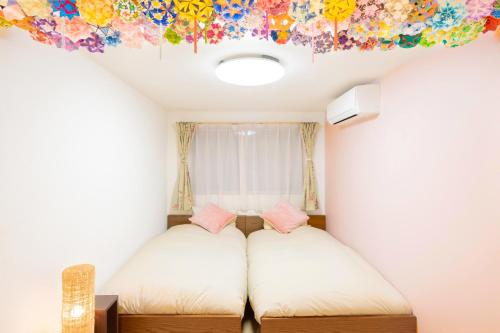 東京にあるCuteFamilyHouse! 3LDK 6minShinjuku 3minJRsta Cozy,Fun,Bright! KidsFree Under6yrsのベッド2台付きの部屋、天井に絵画が飾られた部屋