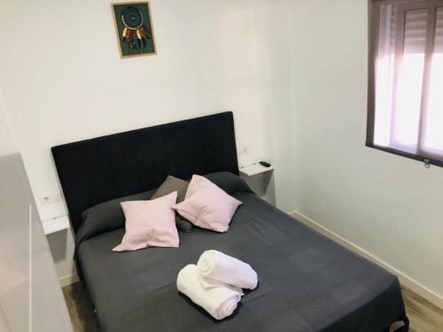 Una cama con almohadas rosas y blancas. en Apartamento CARIHUELA PUERTO en Torremolinos