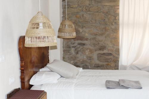1 dormitorio con 1 cama con pared de piedra en El Reposo de la Grulla, en Perales del Puerto