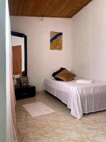 Habitación blanca con cama y espejo en Casa Carolina, en Santa Marta