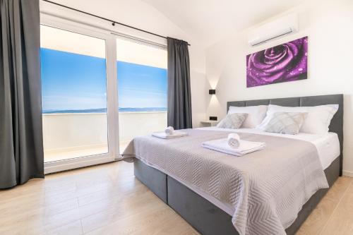a bedroom with a large bed and a large window at Penthouse Nensi in Baška Voda