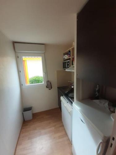 une petite cuisine avec un évier et une fenêtre dans l'établissement Maisonnette à Vieux-Boucau, à Soustons