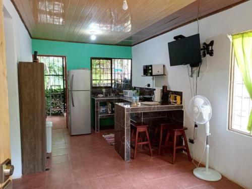 uma cozinha com paredes verdes e um balcão com bancos em La casita JSL 