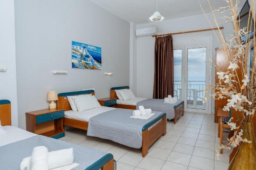 a hotel room with two beds and a balcony at Hotel Galaxias in Paralia Katerinis