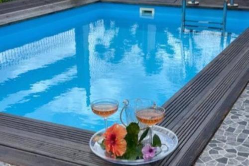 two glasses of wine next to a swimming pool at Palmier bungalow- piscine in Gros-Morne