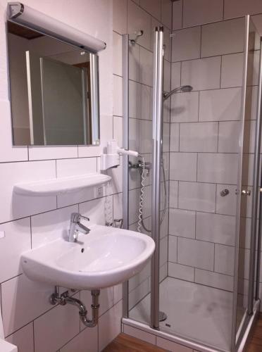 La salle de bains blanche est pourvue d'un lavabo et d'une douche. dans l'établissement Ferienhaus in Feriendorf Silbersee mit Offenem Kamin, à Frielendorf