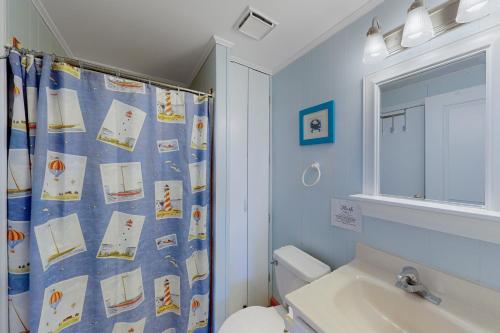 a bathroom with a shower curtain with a toilet and a sink at Dancing Dolphin 106 in Avon