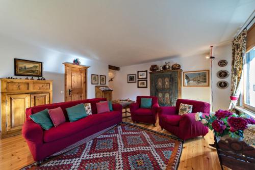 sala de estar con sofá rojo y 2 sillas en Chesa Pradash - Celerina en Celerina