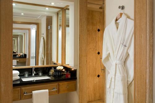La salle de bains est pourvue d'un peignoir blanc. dans l'établissement Hôtel & Ryads Barrière Le Naoura, à Marrakech