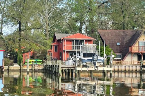 a house on a dock with a boat on the water at Valentine Creek Retreat in Odenton