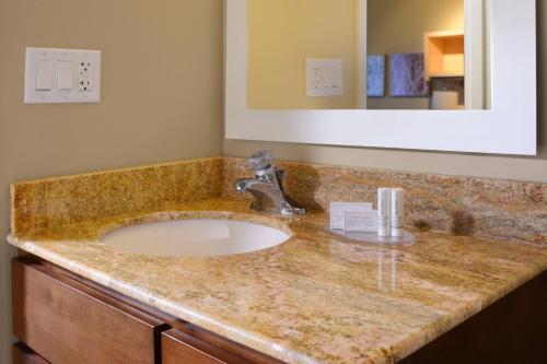TownePlace Suites by Marriott Galveston Island في جالفيستون: منضدة الحمام مع الحوض والمرآة