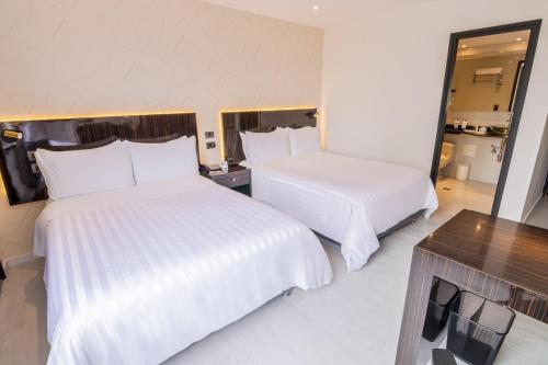Habitación de hotel con 2 camas y espejo en GHL Hotel Portón Medellín en Medellín