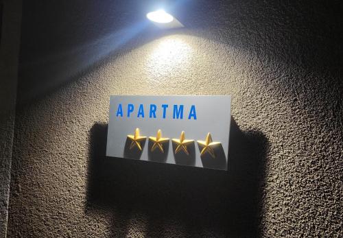 a sign on a wall with four gold lights at Landena Apartments Lendava in Lendava