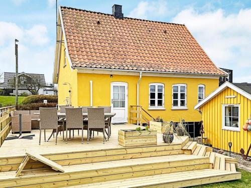 una casa amarilla con una terraza de madera delante de ella en 6 person holiday home in Tranek r en Tranekær