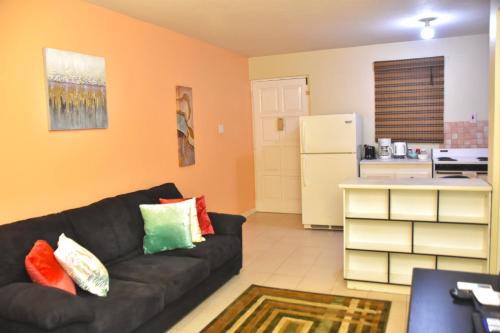 a living room with a black couch and a kitchen at The flat@Waterloo in Kingston