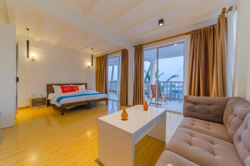 ein Wohnzimmer mit einem Sofa und einem Bett in der Unterkunft Si! Coral Inn in Thulusdhoo