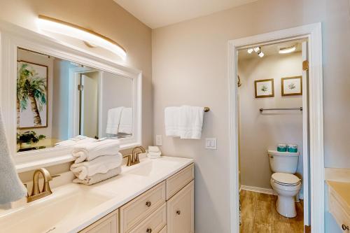 a bathroom with a sink and a toilet and a mirror at Flood Reef Getaway in Pensacola