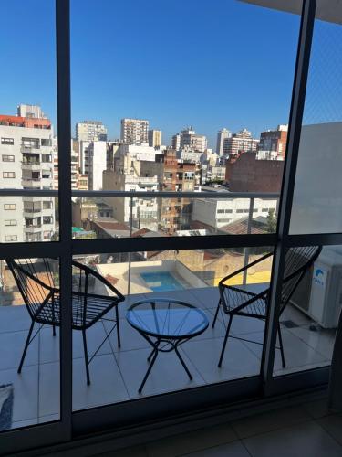 Habitación con vistas a un balcón con 2 sillas y una mesa. en Hermoso apart con piscina en Zona Caballito en Buenos Aires