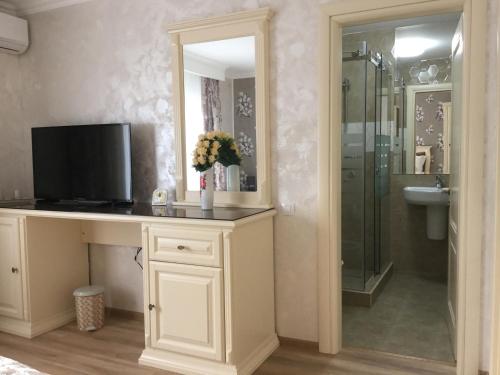baño con lavabo y escritorio con TV. en Vila Royal Mangalia, en Mangalia