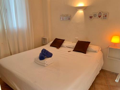 Un dormitorio con una cama blanca con toallas. en Apartments Pepe, Es Pujols-Formentera vacaciones, en Es Pujols
