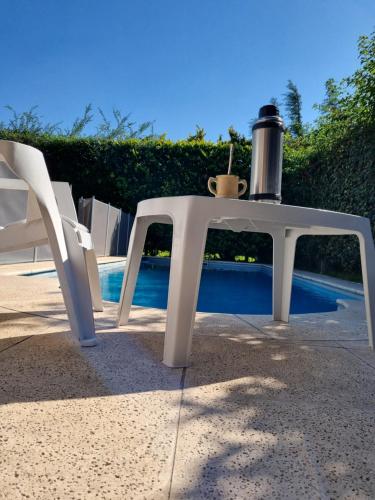 a white table and chair with a drink on it at Casa en barrio cerrado con seguridad 24 horas con piscina in Barrio Esteban Echeverría