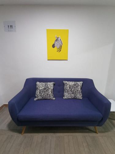 un sofá azul en una sala de estar con una foto en Apartaestudio con 2 camas cerca al centro y parqueadero GRATIS en Popayán