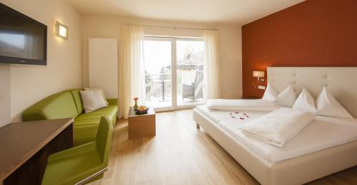 a bedroom with two beds and a couch and a television at Hotel Residence Pernhof in Termeno