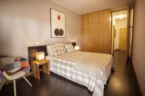 a bedroom with a bed and a chair and a cabinet at Casa do Sol in Porto