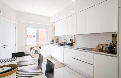 une cuisine avec des placards blancs et une table avec des chaises dans l'établissement Modern Double Room with Private Balcony, à Montijo