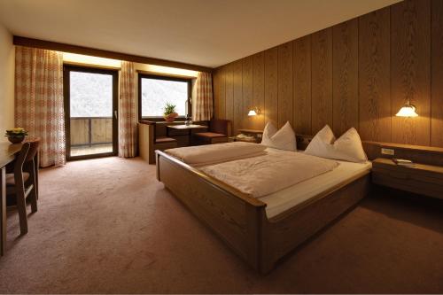 a hotel room with a bed and a desk and window at Hotel Am Fels in Senales