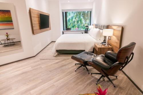 a hotel room with a bed and a desk and chairs at GHL Hotel Portón Medellín in Medellín