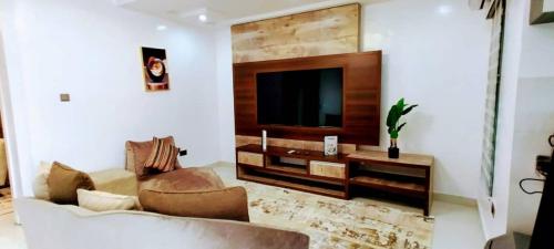a living room with a couch and a flat screen tv at Beautiful One Bedroom Apartment in Opebi, Ikeja in Ikeja