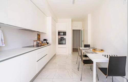 a white kitchen with a long table and chairs at Modern Twin Room with a balcony in Montijo
