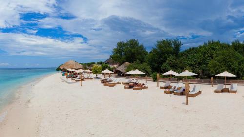 a beach with chairs and umbrellas and the ocean at Pearl of Trawangan in Gili Trawangan