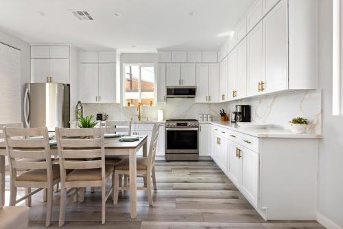 a kitchen with white cabinets and a table and chairs at Adorable 3 bedroom with Jacuzzi & more in Los Angeles