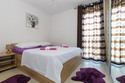 1 dormitorio con 1 cama y una ventana con alfombras púrpuras en Apartments with a parking space Kastel Gomilica, Kastela - 21138, en Kaštela