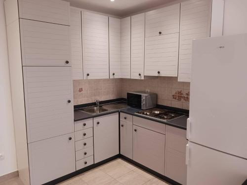 a kitchen with white cabinets and a sink and a refrigerator at Apartments by the sea nska, Krk - 21205 in Malinska