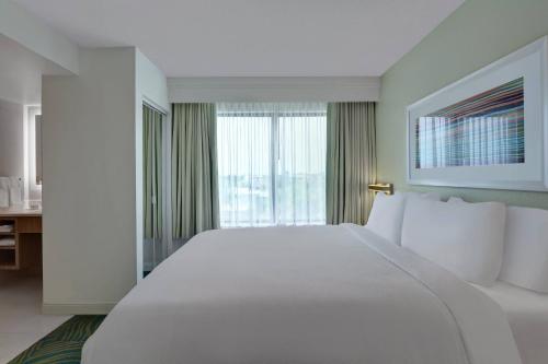 a large white bed in a room with a window at Springhill Suites Jacksonville in Jacksonville