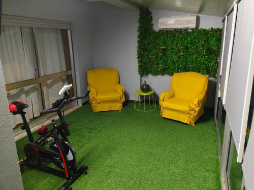a room with two yellow chairs and green carpet at Casa Valadim in Chaves