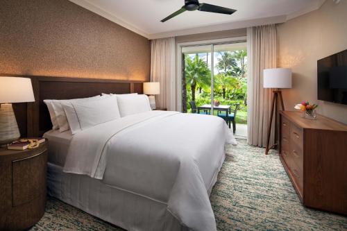 a bedroom with a large white bed and a television at The Westin Princeville Ocean Resort Villas in Princeville